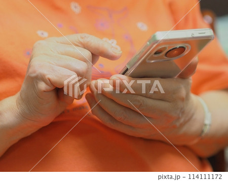 スマホを操作する高齢女性の手元 114111172