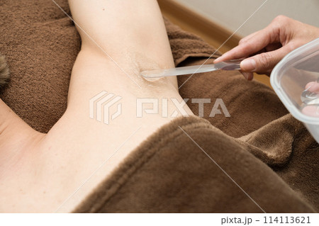 脱毛の施術を受ける男性にジェルを塗る女性の手元 114113621