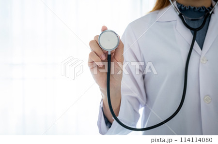 Doctor hand holding stethoscope in front of her with a white background healthcare concept 114114080