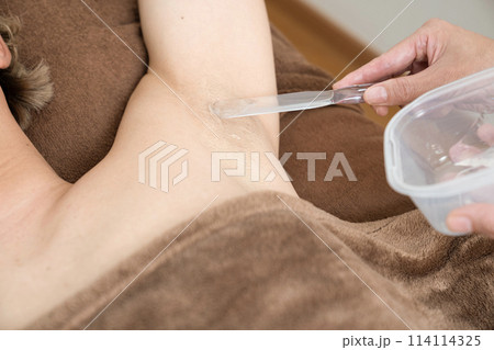 脱毛の施術を受ける男性にジェルを塗る女性の手元 114114325