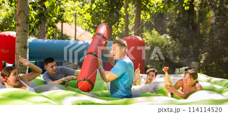 Playful man fighting off friends with inflatable log while guarding toy chickens Playful man fighting off friends with inflatable log while guarding toy chickens 114114520