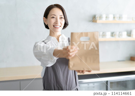 カフェで紙袋を持つ女性店員　テイクアウト 114114661