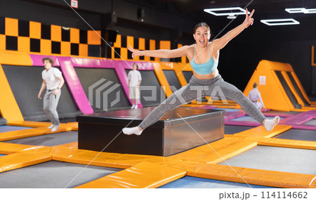 Young woman in sport clothes high jumping in trampoline arena 114114662