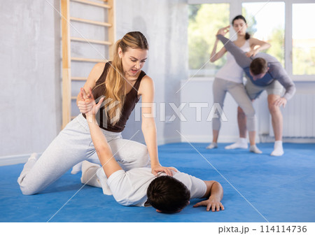 Young woman twisting her opponent's arm during self-defense classes Young woman twisting her opponent's arm during self-defense classes 114114736