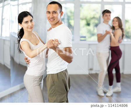 Young couple enjoying slow foxtrot in dance studio 114114806
