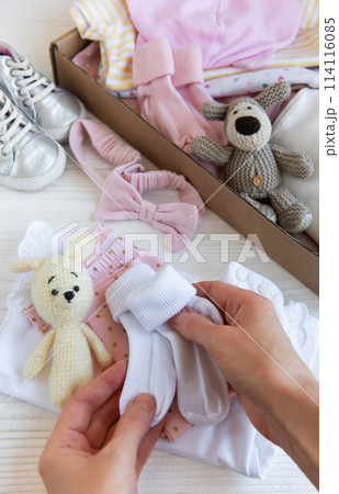 Women's hands collect children's clothes into boxes. Women's hands collect children's clothes into boxes. 114116085