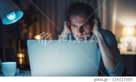 スクリーンを深刻な顔で見る男性 Man seriously looking into monitor 114117305