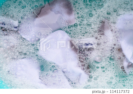 Dirty white socks soaked in water, dissolving detergent in blue basin. 114117372