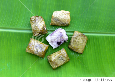 Bundled boiled sticky rice with banana and black beans wrapped in banana leaves 114117495