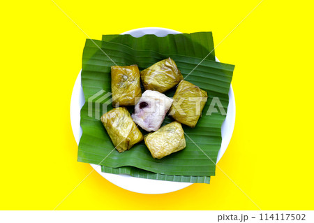 Bundled boiled sticky rice with banana and black beans wrapped in banana leaves 114117502