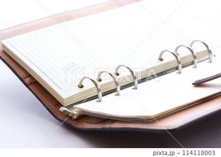 リング式のシステム手帳を開いてデスクワークをしているイメージ 114118003
