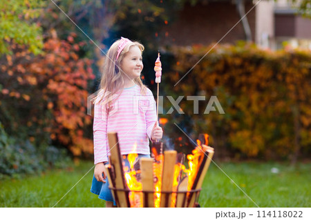 Child with smores at fire. Kids roast marshmallow. 114118022