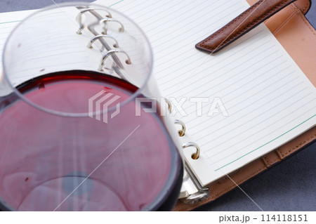 リング式のシステム手帳と赤ワインのグラス 114118151