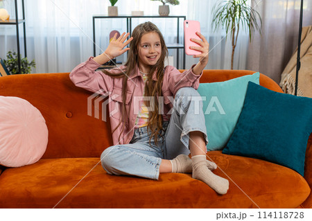 Happy child girl blogger taking selfie on smartphone communicating video call with subscribers 114118728
