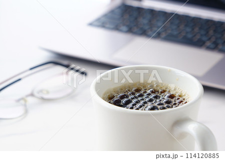 淹れたての美味しいコーヒーを飲みながら、ノートパソコンでデスクワークをしているイメージ 114120885