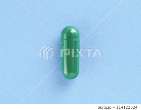 Green two-piece hard starch capsule on blue background with copy space. Medical and Health concept. 114122624