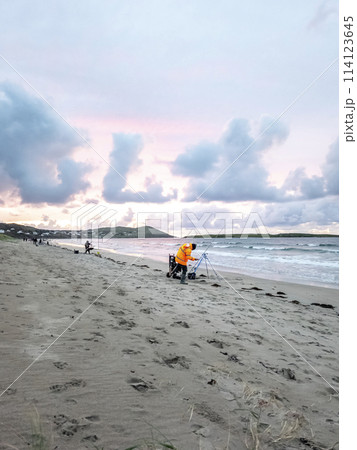 20 man are competing in a fishing competition on the beach. 114123645
