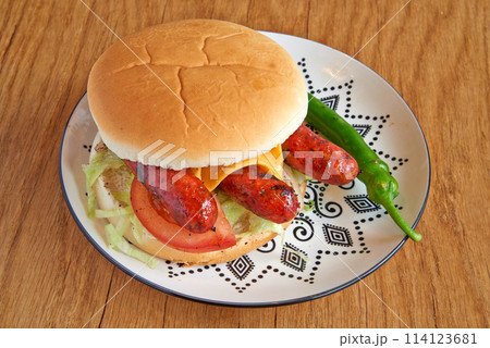 Merguez burger on decorated plate on wooden textured table 114123681