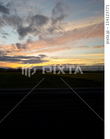 夕焼けの中に映える飛行機雲 114123771
