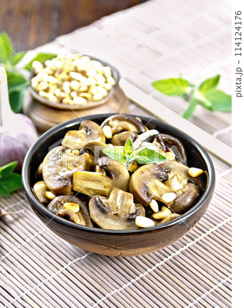 Champignons with oregano and nuts in bowl on brown napkin 114124176