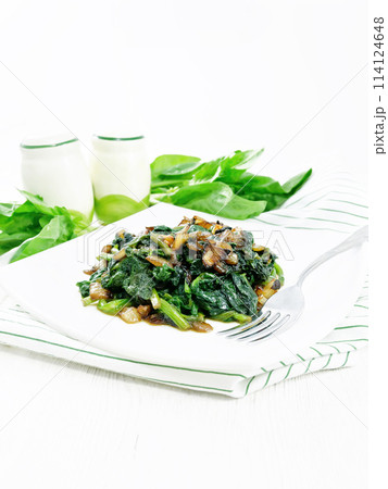 Spinach fried with onions in plate on towel Spinach fried with onions in plate on towel 114124648
