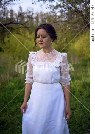 beautiful woman in white vintage dress with train in spring garden at sunset beautiful woman in white vintage dress with train in spring garden at sunset 114125147