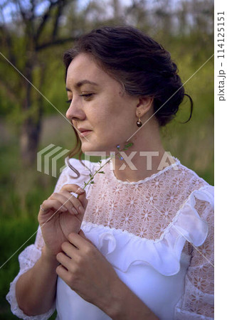 beautiful woman in white vintage dress with train in spring garden at sunset 114125151