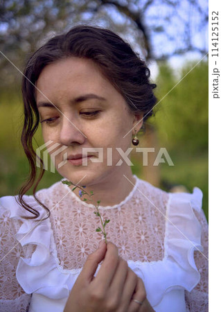 beautiful woman in white vintage dress with train in spring garden at sunset 114125152