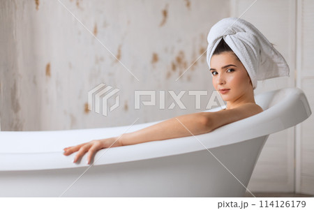 Relaxed young woman laying in bathtub 114126179