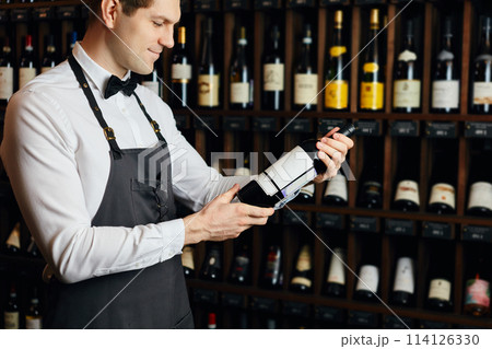 Sommelier presenting bottle of red wine to customer in a wine store Sommelier presenting bottle of red wine to customer in a wine store 114126330