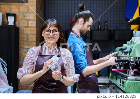 Teamwork, man and woman in aprons working together at bar counter in coffee shop cafe Teamwork, man and woman in aprons working together at bar counter in coffee shop cafe 114126829