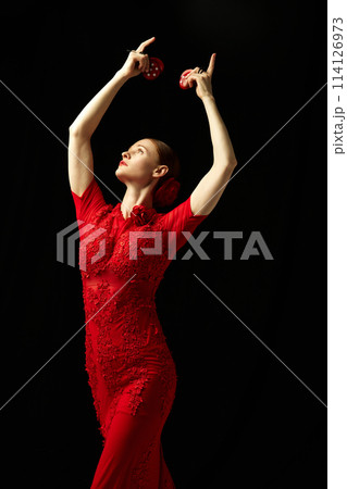 Elegant woman in beautiful red dress performing with castanets against black background. Following Spanish traditions Elegant woman in beautiful red dress performing with castanets against black background. Following Spanish traditions 114126973