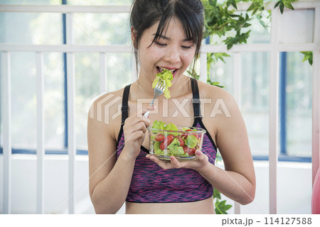 Wellness Asian women dressing organic green salad tomato vegetable dish. Beautiful girl healthcare vegan wellness lifestyle concept. Healthy woman workout holding organic salad bowl healthy lifestyle 114127588