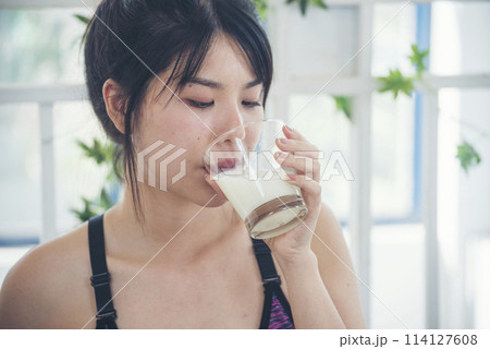 Women hands holding white glass of milk pouring from bottle. Asian women smile laugh look at camera health care home fitness lifestyle. Beautiful female drinking fresh milk low-fat dairy free lactose 114127608