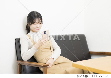 ソファでスマホを使用している若い女性 114127998
