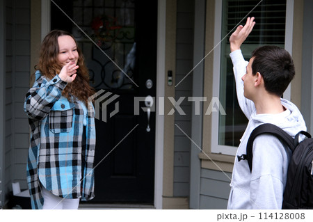 Young people, man and woman greeting or saying goodbye by waving hands in the park. 114128008