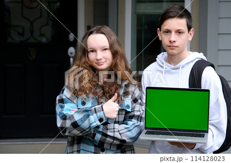 teenagers boys girl holding green screen laptop girl showing thumb up promoting product online learning games shopping fun entertainment school supplies 114128023