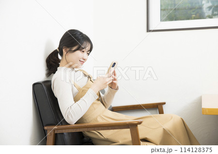 ソファでスマホを使用している若い女性 114128375