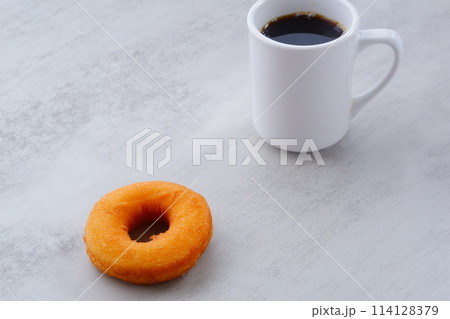 リング状のドーナツと、白いマグカップに入ったコーヒー リング状のドーナツと、白いマグカップに入ったコーヒー 114128379