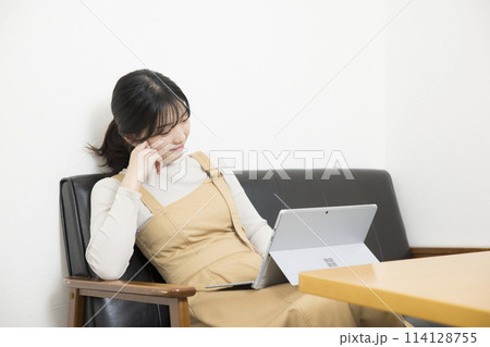 ソファに座ってPCを使用する若い女性 114128755
