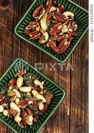 Mixed nuts in a bowl on wooden background. 114128859