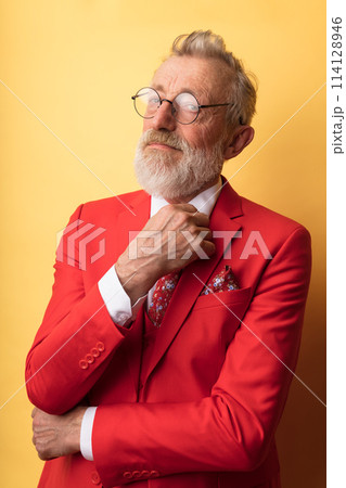 Old-aged dandy in red suit with necktie in floral print smiling at camera Old-aged dandy in red suit with necktie in floral print smiling at camera 114128946
