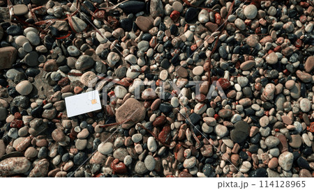 mound of rocks, each boasting unique blend of colors and sizes, epitomizing the allure of natural beauty and ruggedness, with a white bank card, juxtaposing human convenience against nature's rawness. mound of rocks, each boasting unique blend of colors and sizes, epitomizing the allure of natural beauty and ruggedness, with a white bank card, juxtaposing human convenience against nature's rawness. 114128965