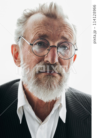 Old bearded man in black suit and elegant round spectacles looking at camera. 114128966