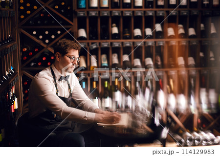 Portrait of confident male sommelier tasting red wine. Winemaking. Occupations. Portrait of confident male sommelier tasting red wine. Winemaking. Occupations. 114129983