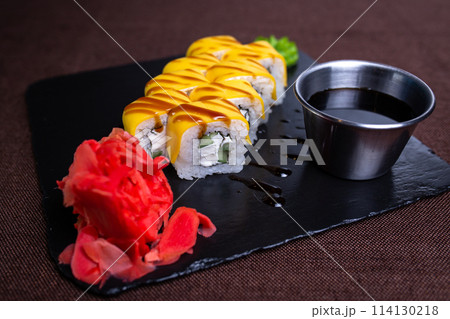 Sushi roll with cream cheese, cucumber, and eel topped with yellow sauce 114130218