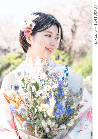 桜の中を歩く卒業式前撮りの若い女性 114130437