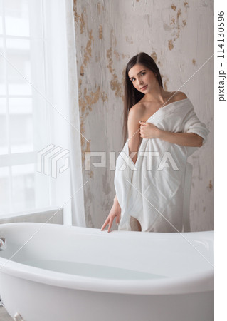 Beautiful young brunette woman posing in a bathrobe 114130596
