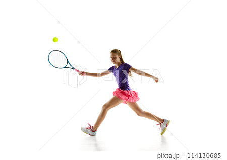 Focused on game young girl, tennis player in vibrant uniform ready to serve ball to opponent against white studio background. 114130685