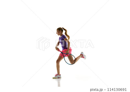 Portrait of young sportive teenager, female tennis player in uniform training in motion against white studio background. 114130691